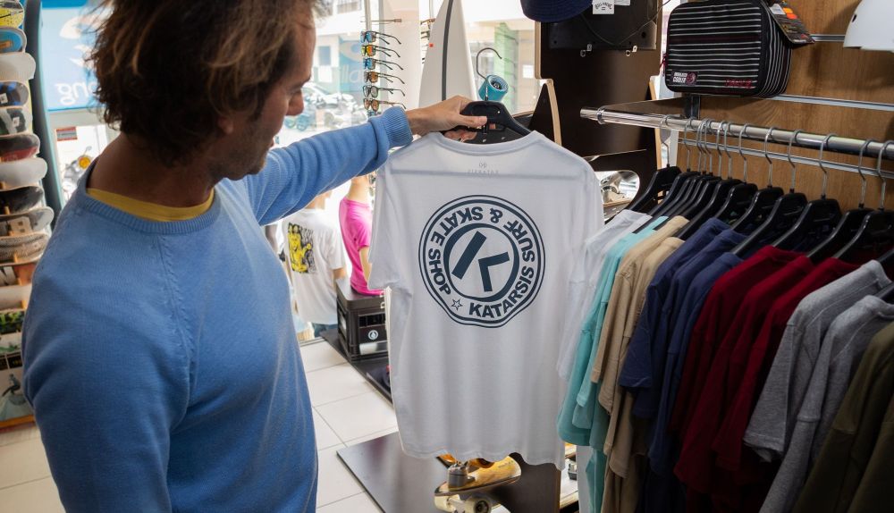 Antonio muestra las camisetas de la colección con el logo de la tienda.