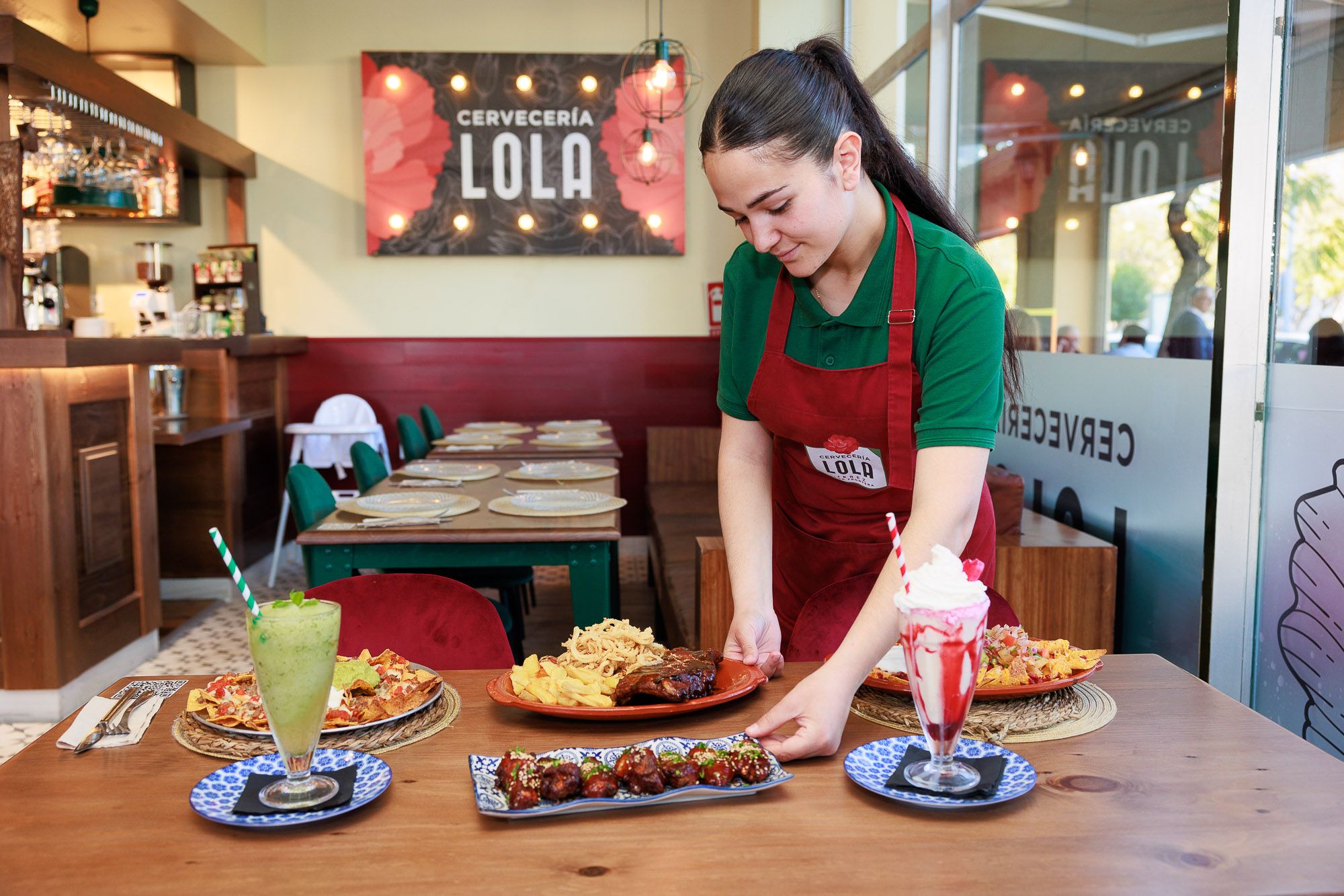 Una trabajadora de Cervecería Lola, con platos de nachos en el establecimiento.