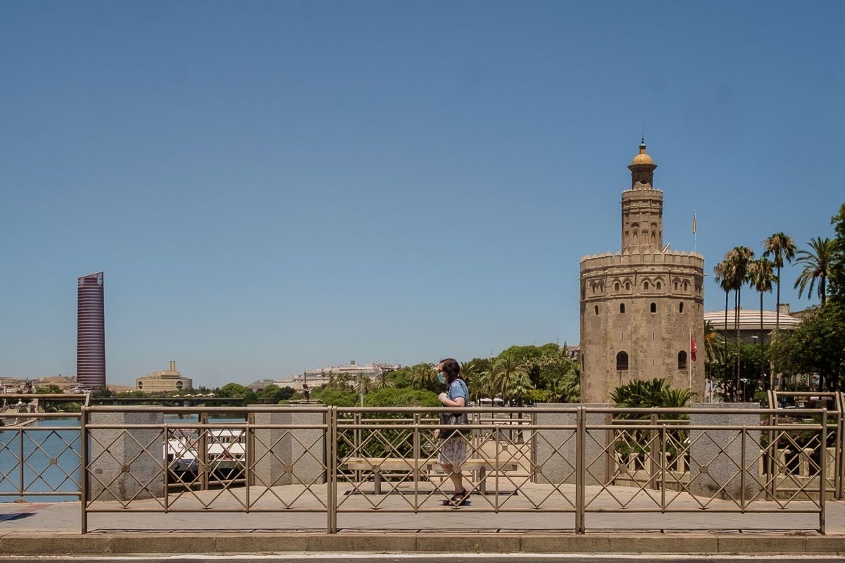Una mujer, con la Torre Pelli y la Torre del Oro al fondo, en una imagen reciente de Sevilla. FOTO: MANU GARCÍA