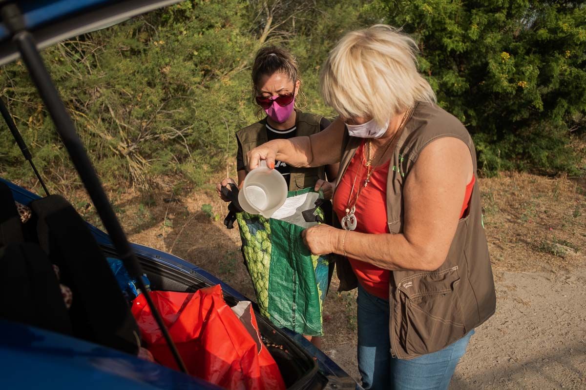 María del Carmen Heredia y una voluntaria recargando los recipientes con pienso para los gatos. FOTO: MANU GARCÍA