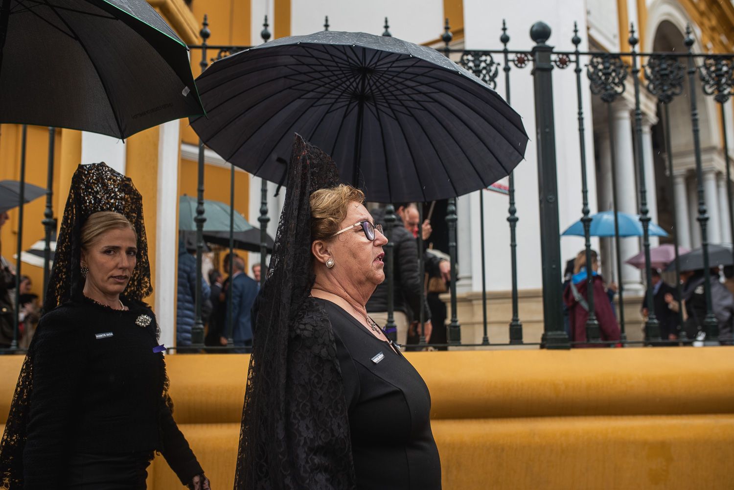 Dos mujeres, con mantilla y bajo el paraguas, este Jueves Santo en Sevilla.