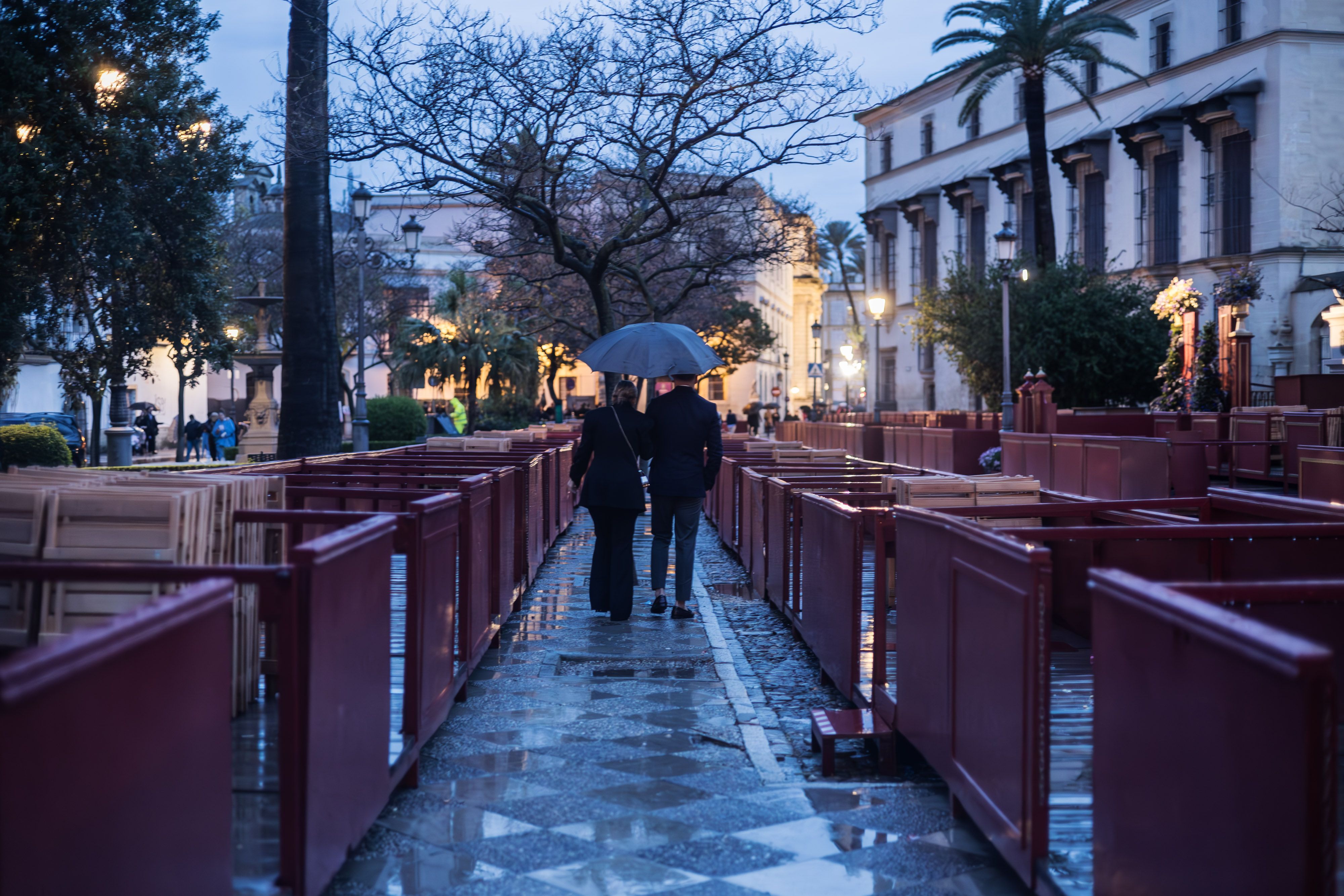 Una pareja paseando bajo la lluvia entre los palcos de plaza Aladro Una pareja paseando bajo la lluvia entre los palcos de plaza Aladro