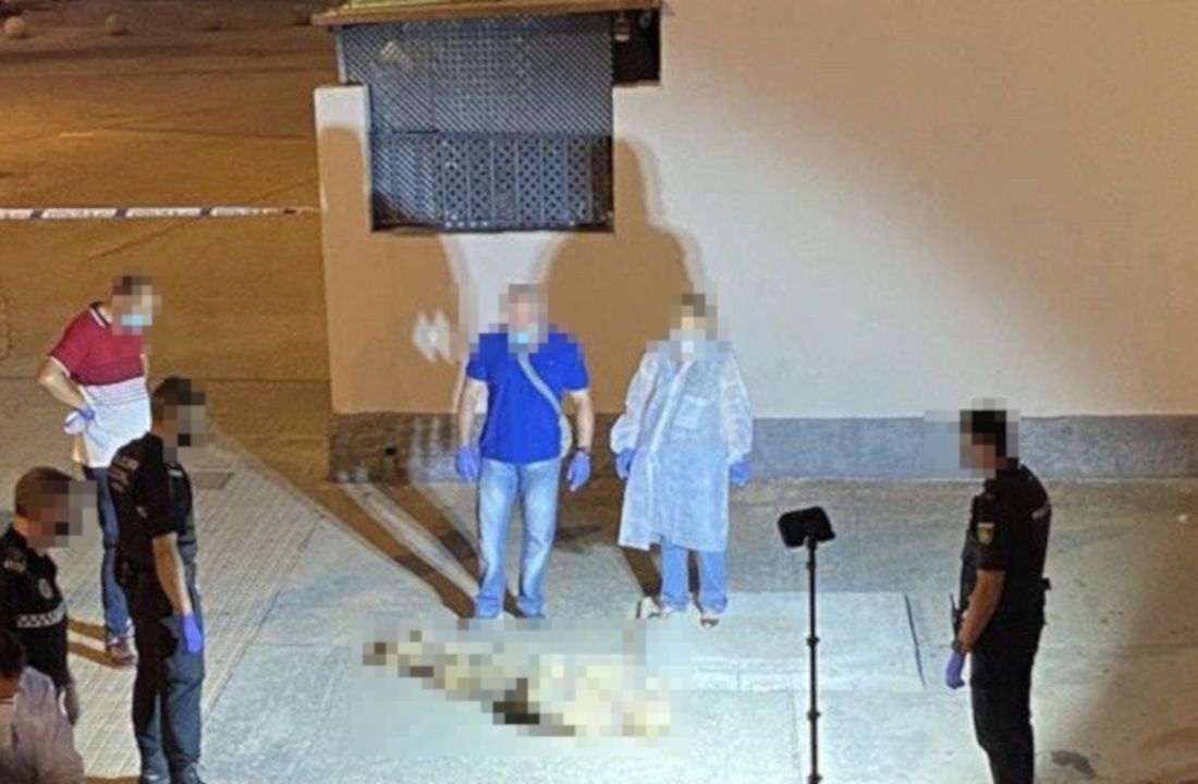 Las fuerzas de seguridad trabajando sobre el lugar de los hechos, con el cuerpo de la mujer envuelto en el centro, pixelado.