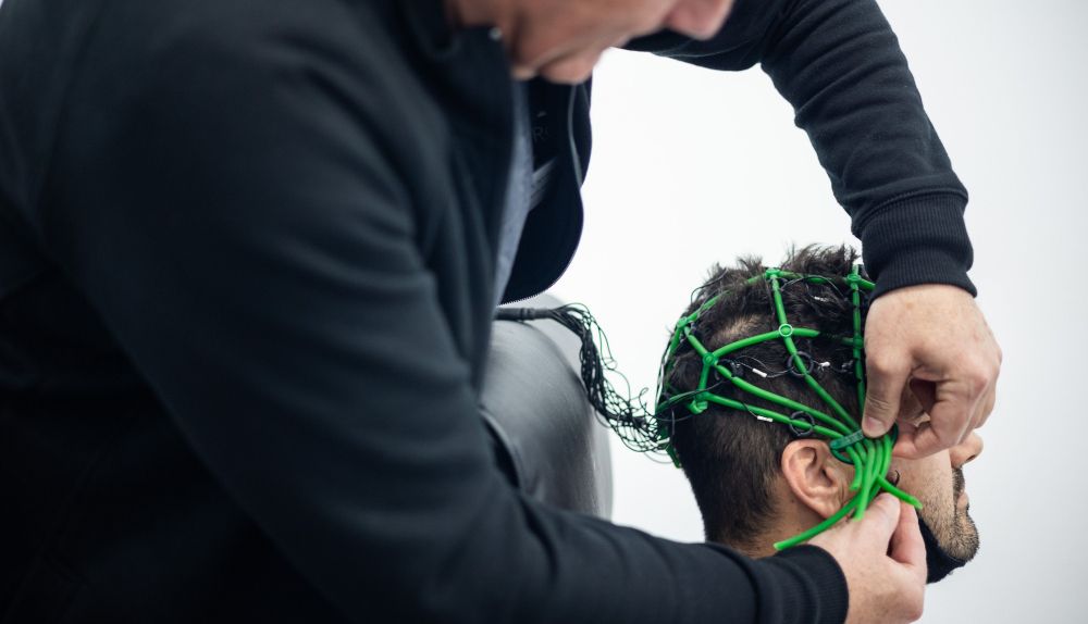 El neuropsicólogo coloca el casco al paciente.