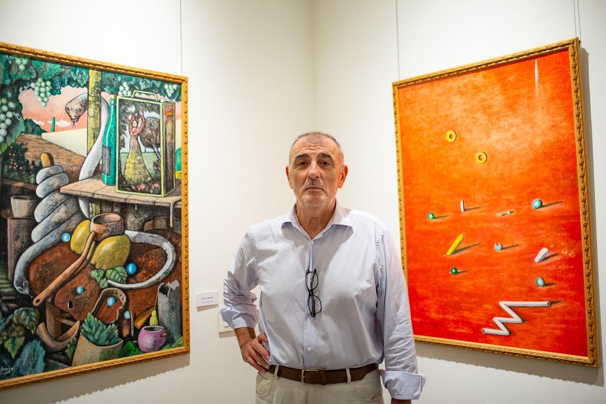 Ramón Epifanio, con dos de sus cuadros al fondo, en la exposición 'Los colores del alma', que expuso este verano en Los Claustros. Autor: JUAN CARLOS TORO