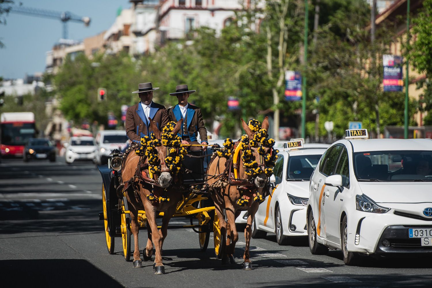 Un coche de caballos, junto a taxis y un autobús cerca del recinto de la Feria de Sevilla.