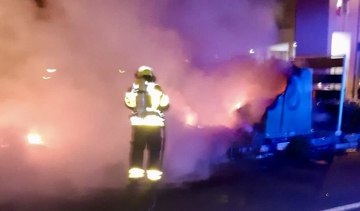 Un bombero, apagando un contenedor quemado.
