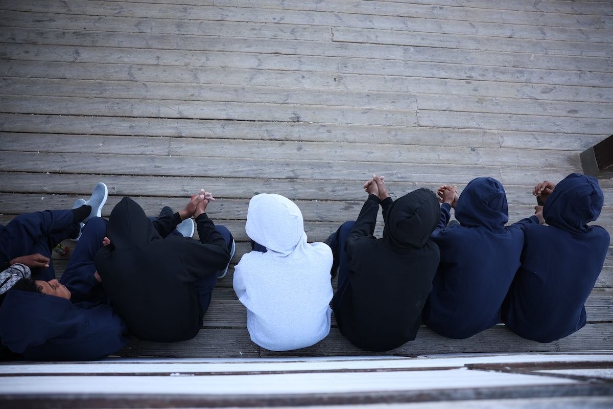 Los migrantes llegados a la playa Victoria en abril, sentados en el chiringuito bajo el Paseo Maritimo.   JUAN CARLOS TORO
