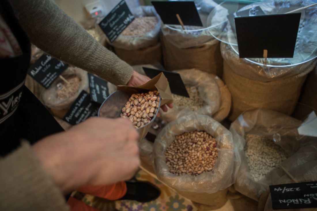 Cesta de la compra. Una mujer despachando unas legumbres a granel.