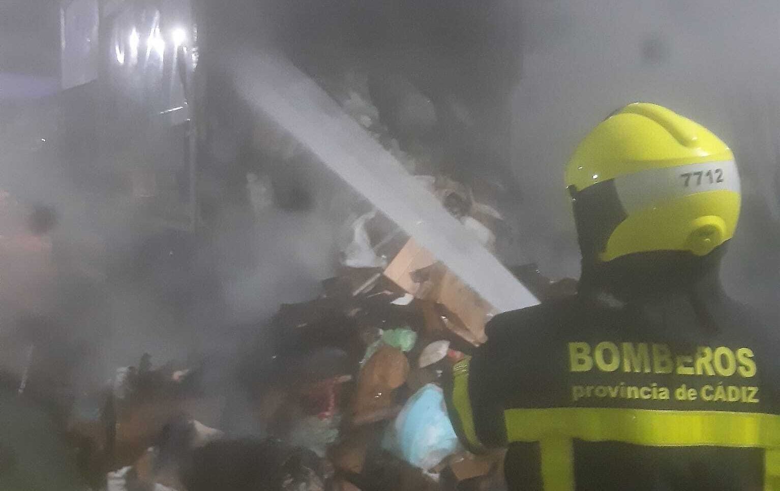Un bombero, extinguiendo el fuego en contenedores de Jerez.