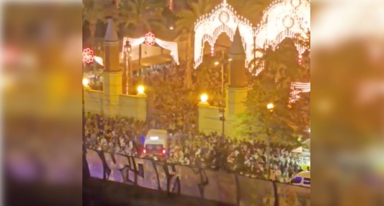 Una ambulancia intenta acceder al Real de la Feria entre la multitud.