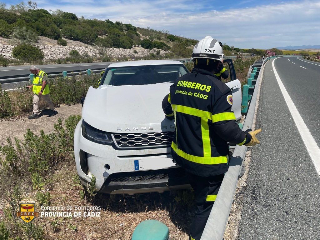 Vehículo accidentado en la Jerez-Los Barrios, este pasado jueves, junto a efectivos de Bomberos.