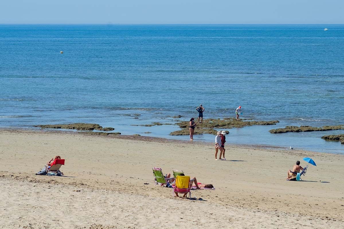 Personas paseando por la playa, donde es obligatorio el uso de mascarilla.
