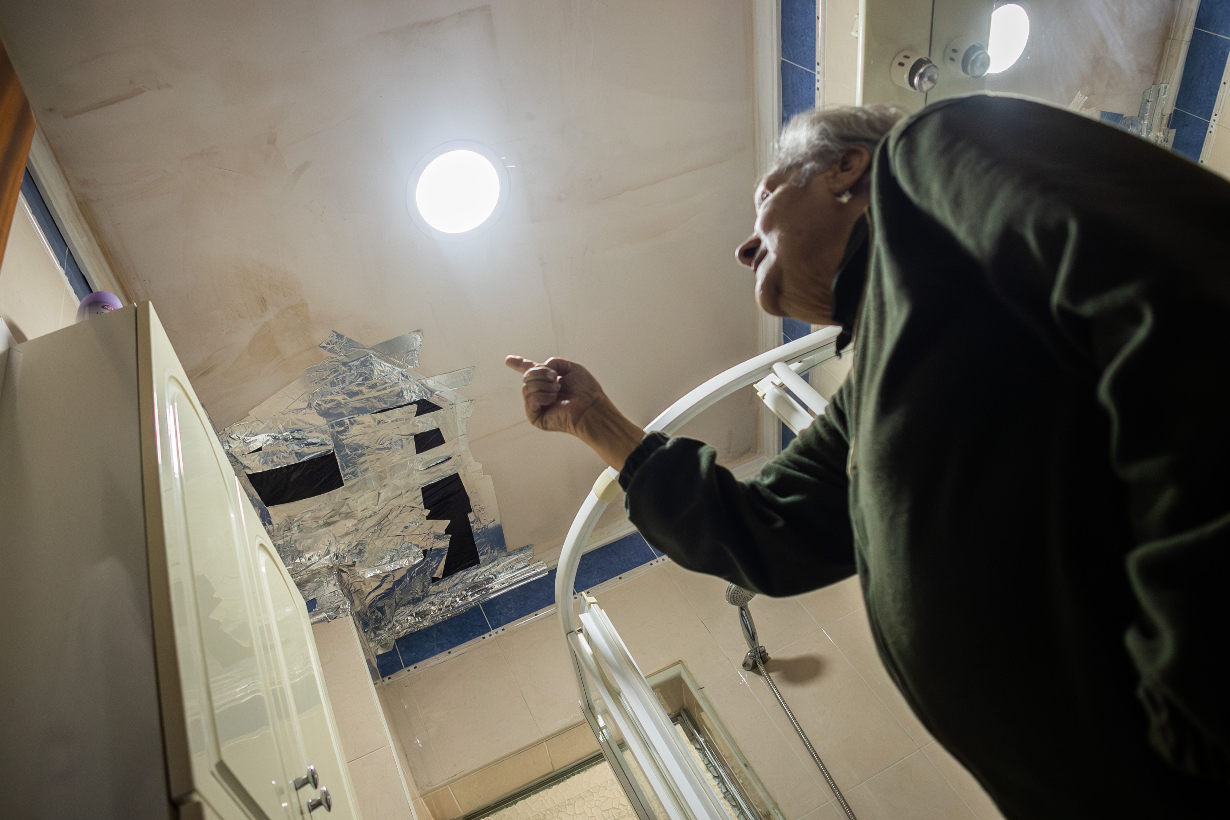 Josefa señala el techo de su baño, abierto tras la rehabilitación, por lo que se inunda cada vez que llueve.