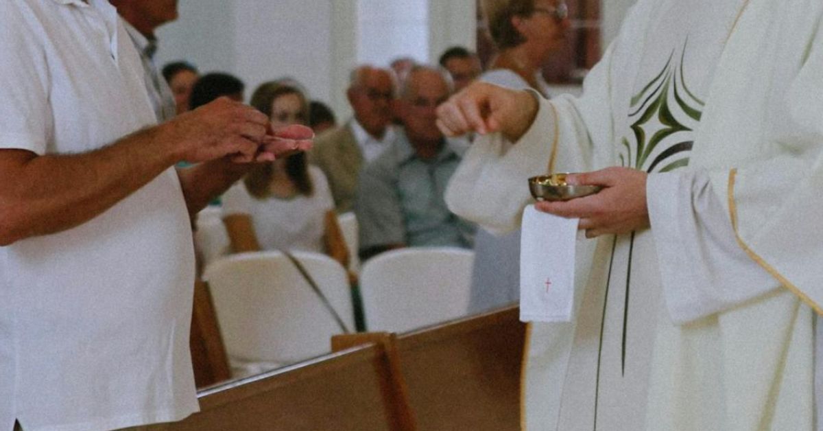 Un cura da la comunión durante una misa.