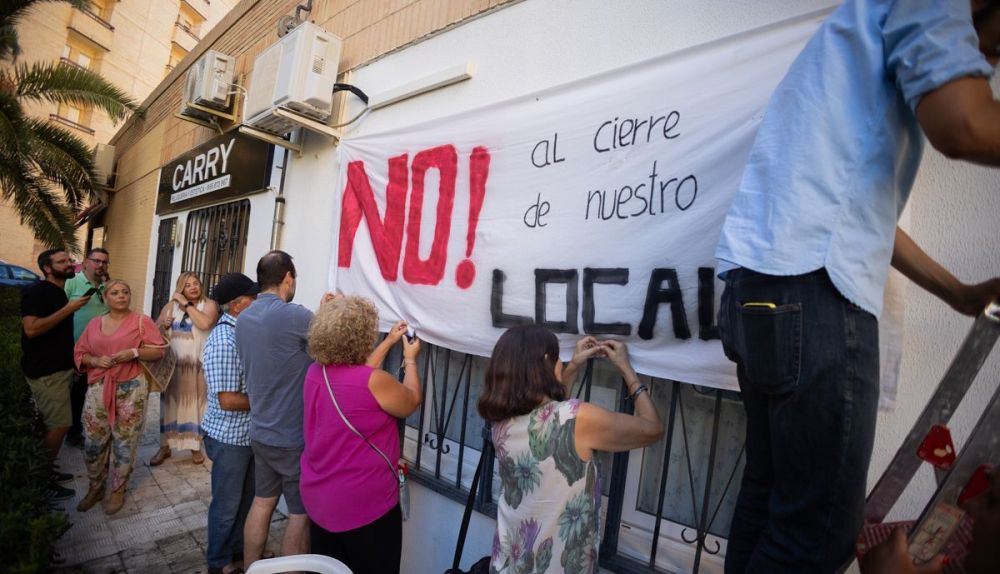 Varios vecinos de Fermesa colocando una pancarta reivindicativa en el local.