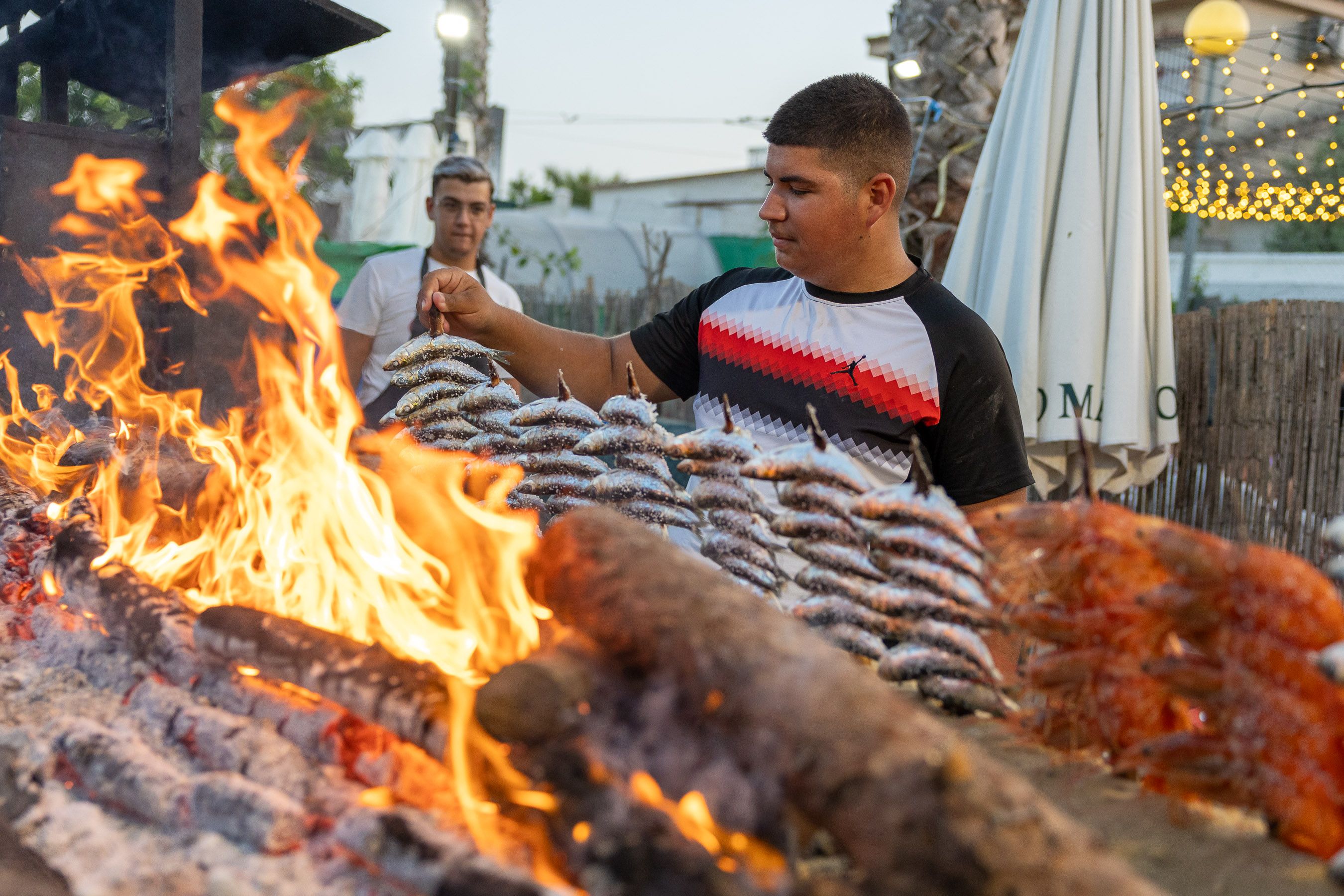 Sardinas y gambones en espetos poniéndose a punto en la candela.