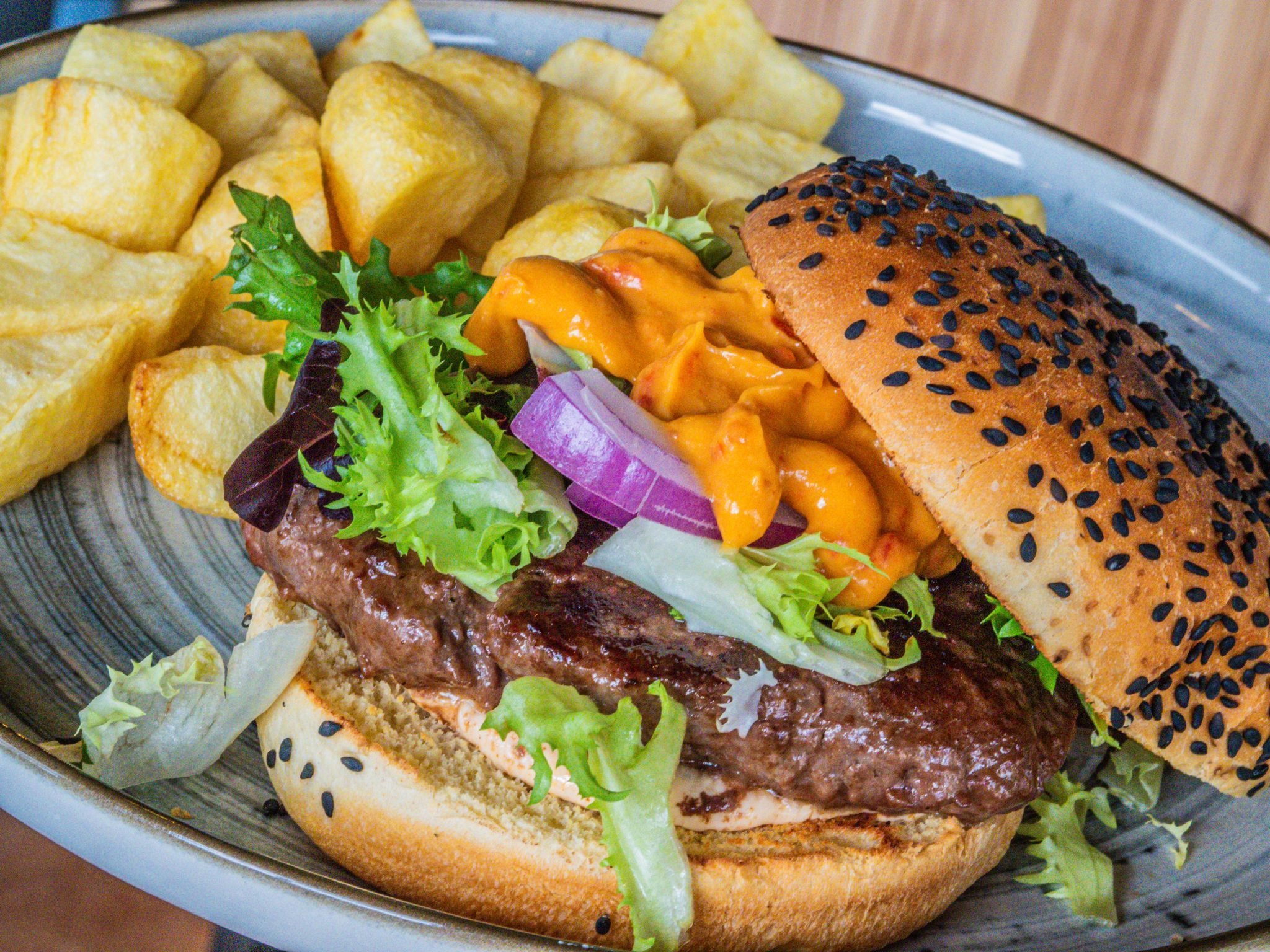 Hamburguesa con patatas, un clásico que no falla en la carta de Playa Dulce.