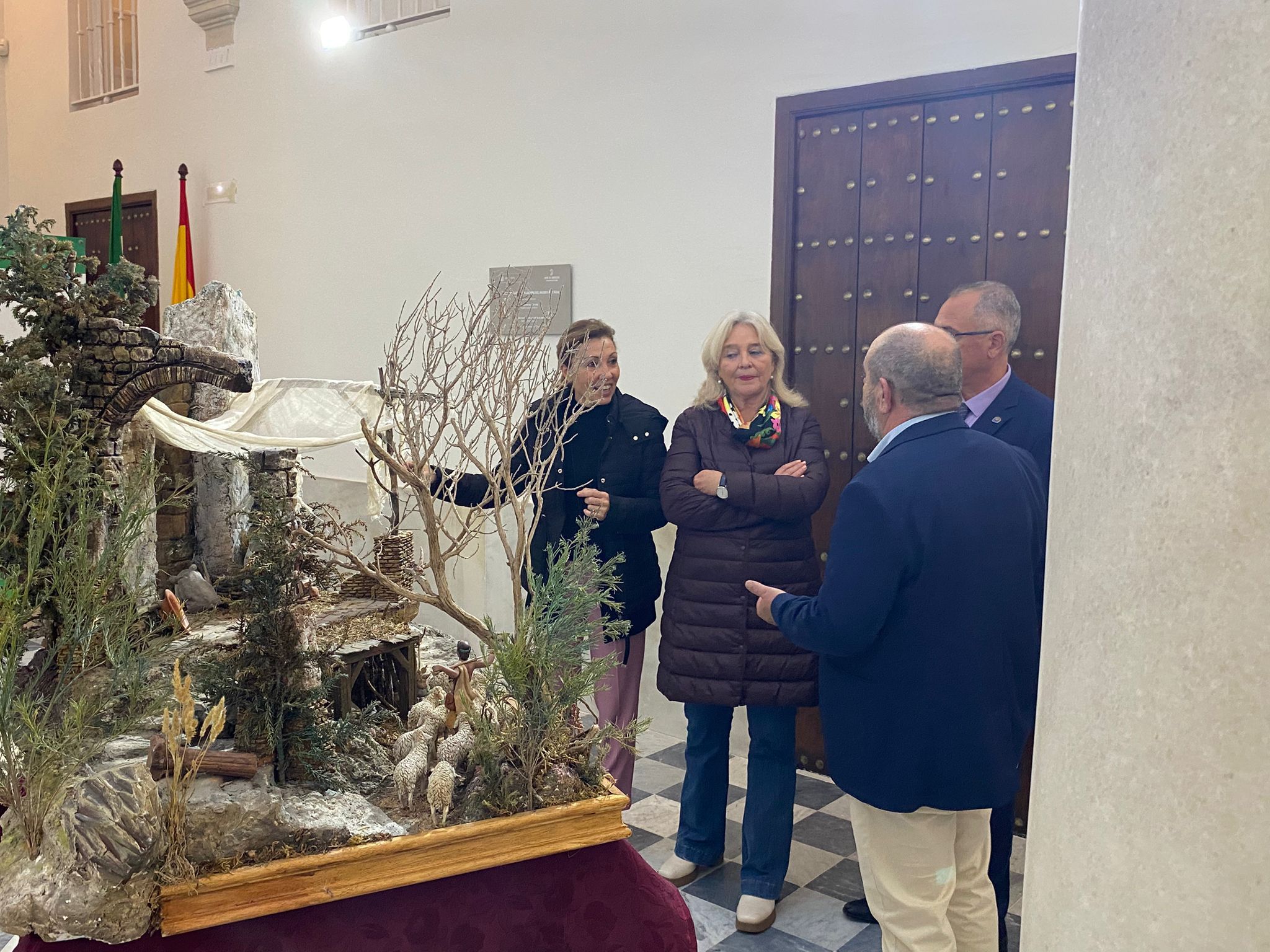La delegada y los belenistas portuenses visitando el nacimiento instalado en la casa Pinillos.