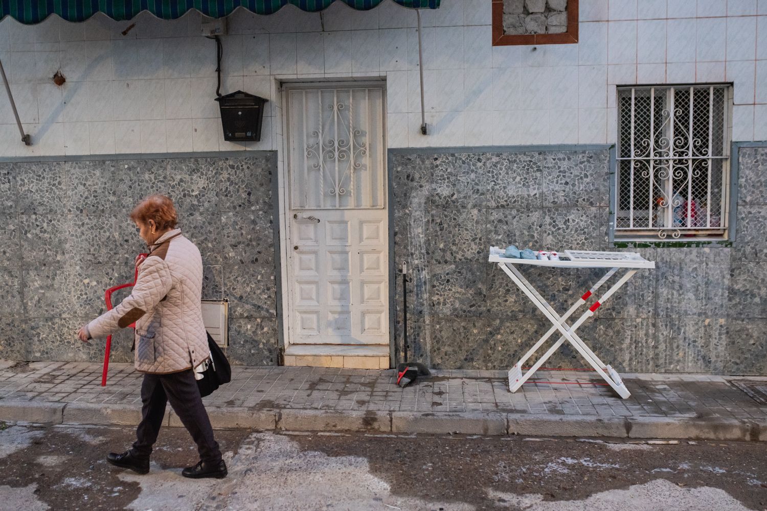Una vecina pasa junto a una casa en el barrio sevillano de Amate, uno de los más pobres de España.