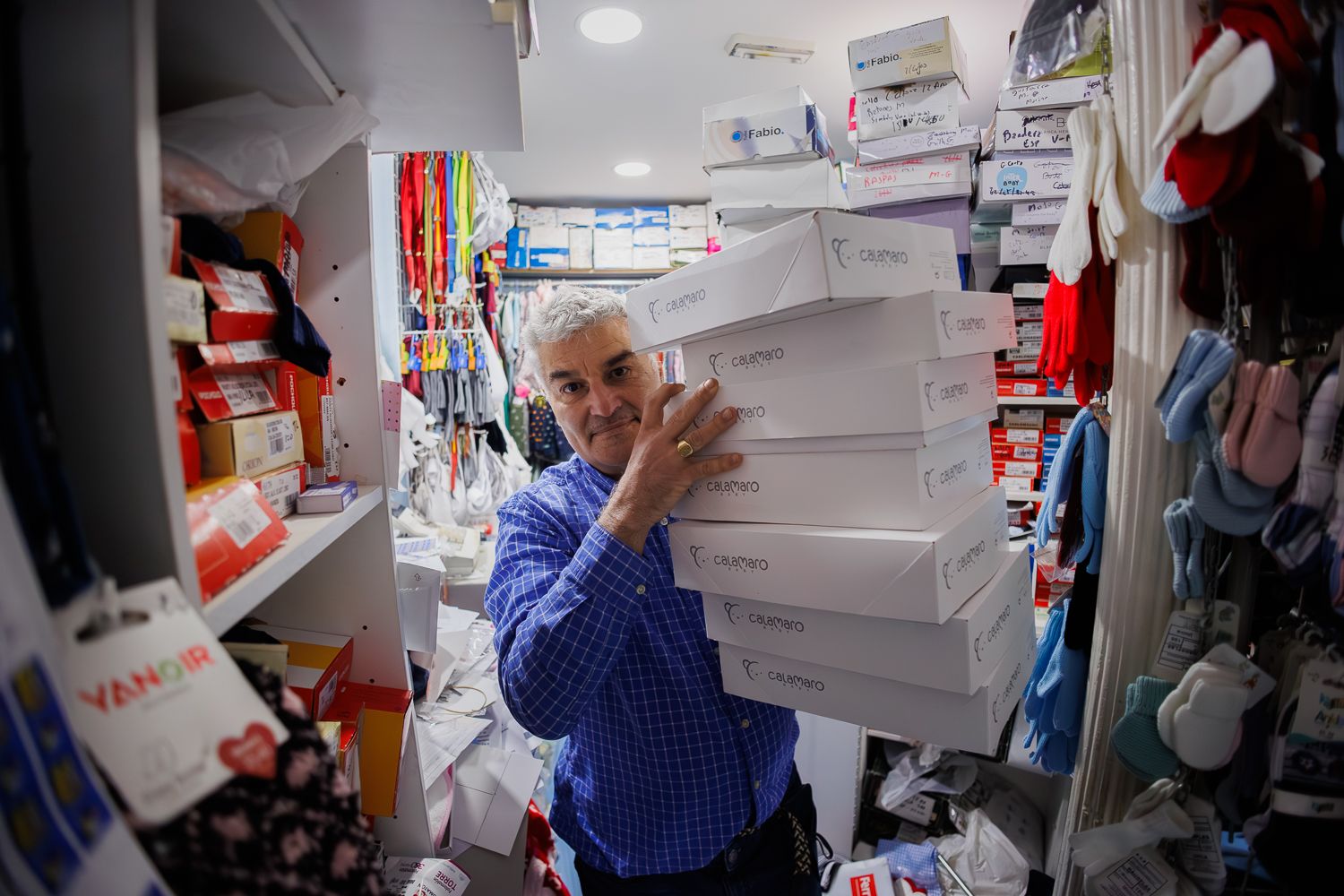 Manuel Anguita cargado de cajas en el interior de la tienda.  