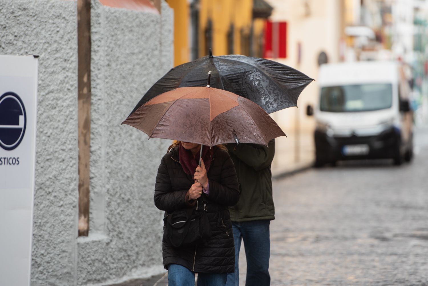 Dos personas se refugian de la lluvia bajo sus paraguas en Andalucía. Dos personas se refugian de la lluvia bajo sus paraguas en Andalucía.