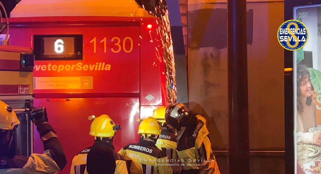 Bomberos cortan la chapa de la marquesina desprendida por el impacto del autobús en Sevilla.