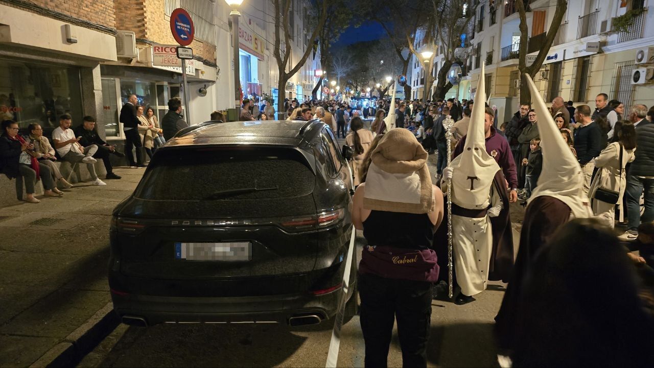 Un coche, durante el paso de La Entrega por calle Santo Domingo, a la salida del centro de Jerez.