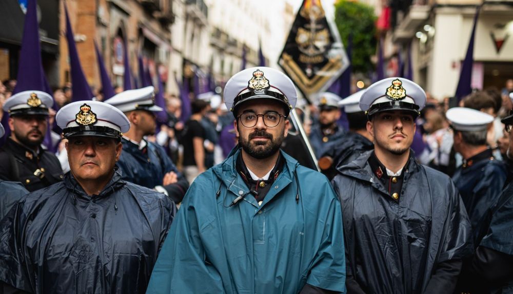 Músicos del Rosario de Cádiz, formación titular de Las Aguas, protegidos con capotes por la lluvia del pasado Lunes Santo en Sevilla.
