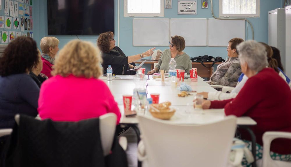 Marita y X leen a las vecinas.