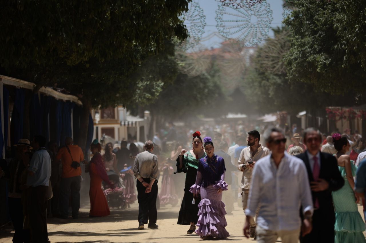 Varias personas pasean entre el polvo en la Feria de Jerez.