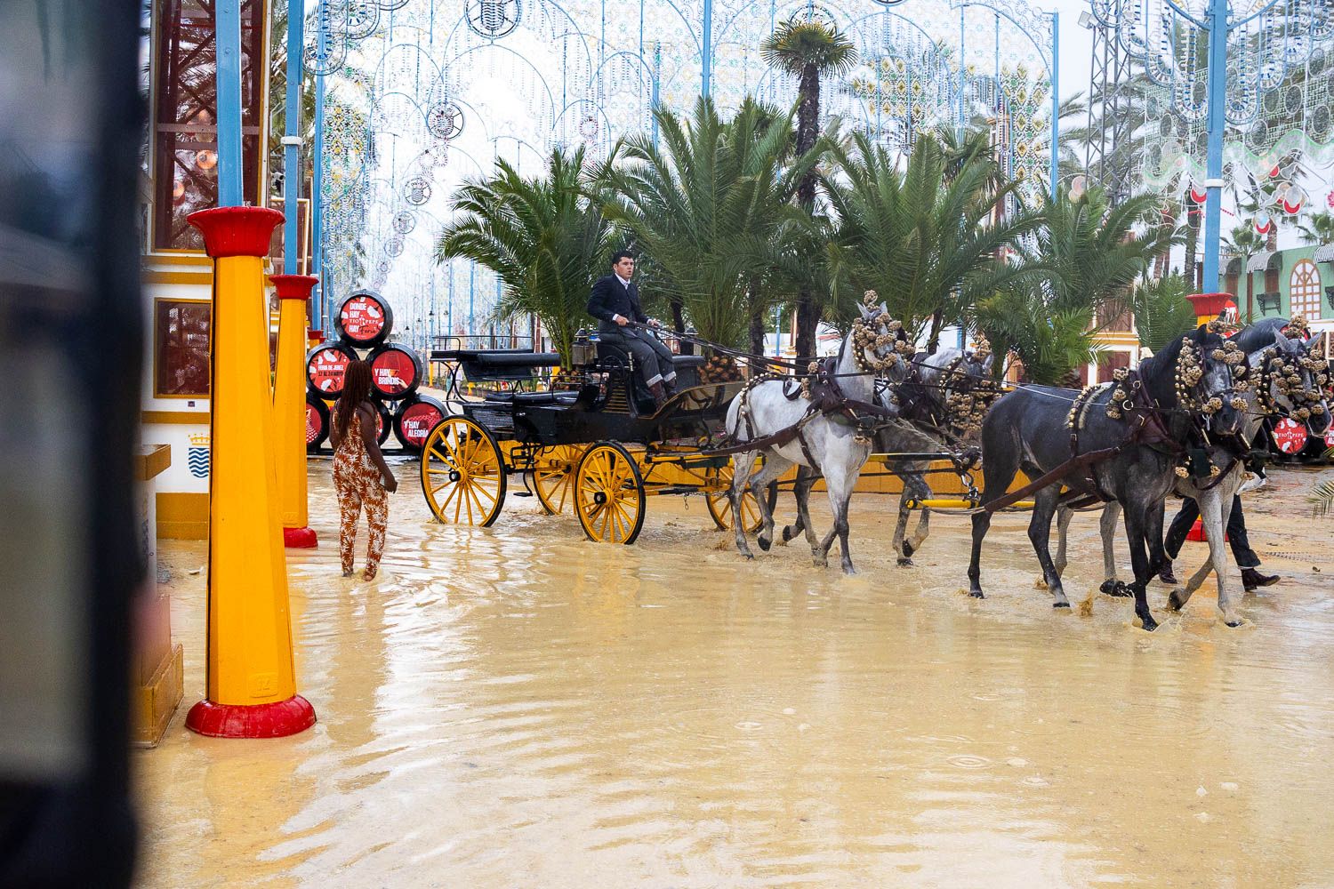Coches de caballo sobre los charcos formados tras la aparición de la lluvia el viernes de feria de 2025 en Jerez.