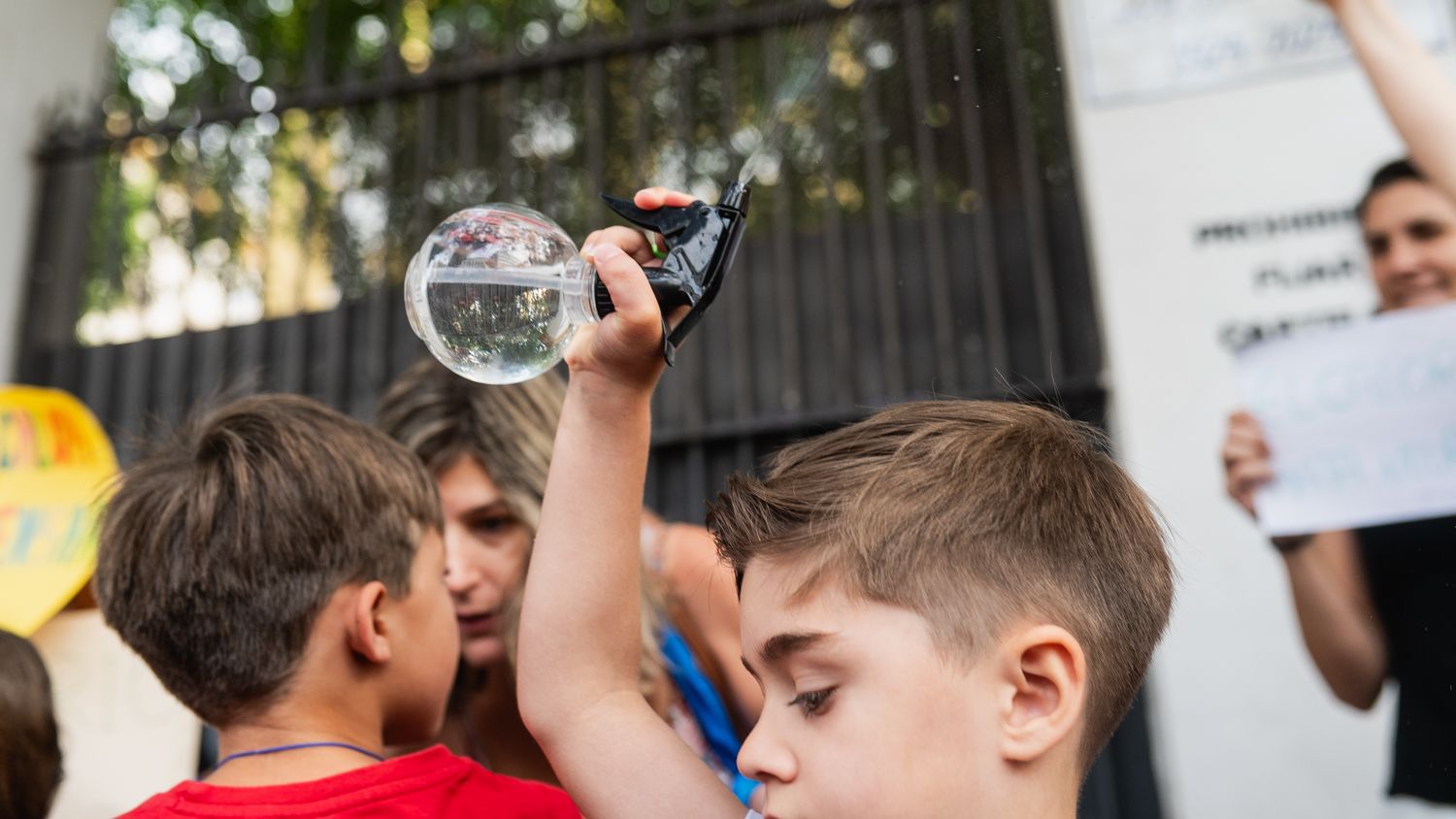Un niño, echándose agua por encima en protestas por el calor en las aulas en Sevilla.