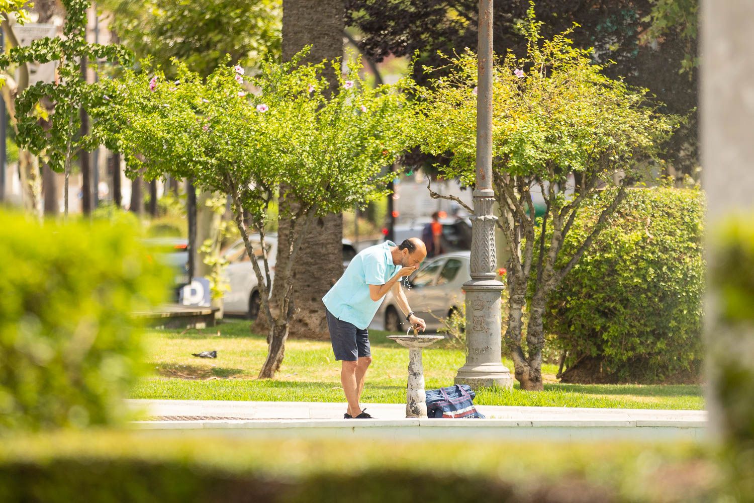 Un hombre se echa agua de una fuente para soportar el calor.