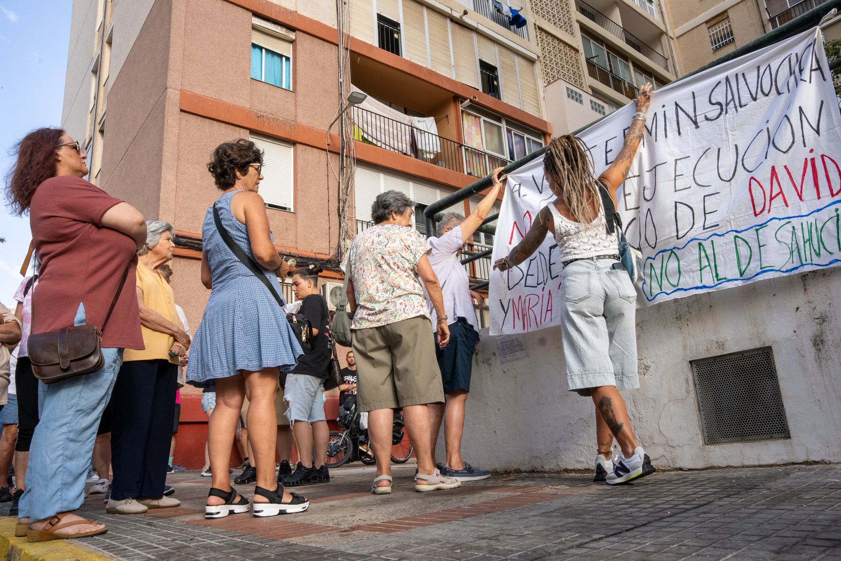 Amigos, vecinos y familiares colocan una pancarta frente a la vivienda a desalojar.