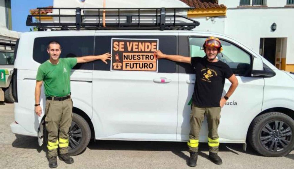 Dos bomberos, con uno de los carteles reivindicativos.