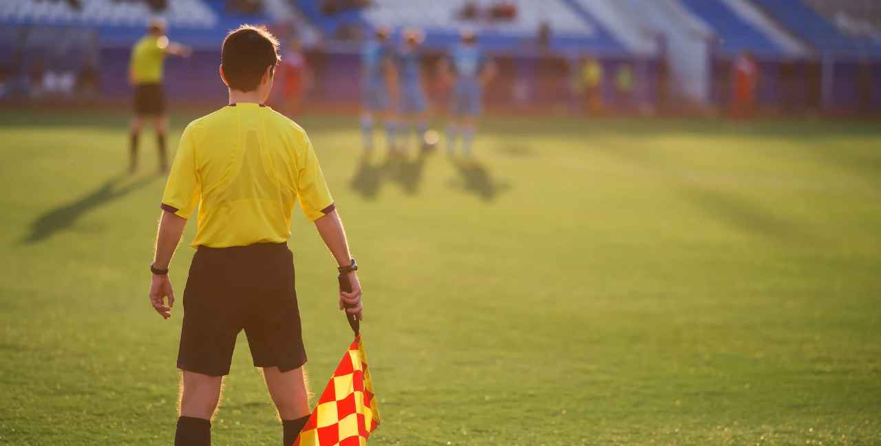 Imagen de un árbitro asistente en un partido de fútbol base.