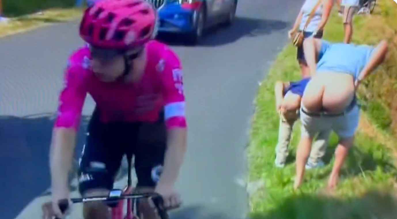 Dos aficionados, haciendo un calvo durante el paso de un ciclista.