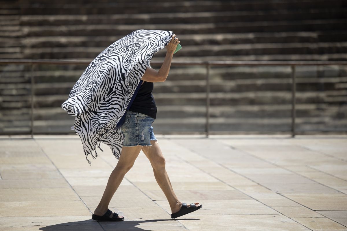 Una persona se cubre del sol mientras camina por el centro de Málaga.