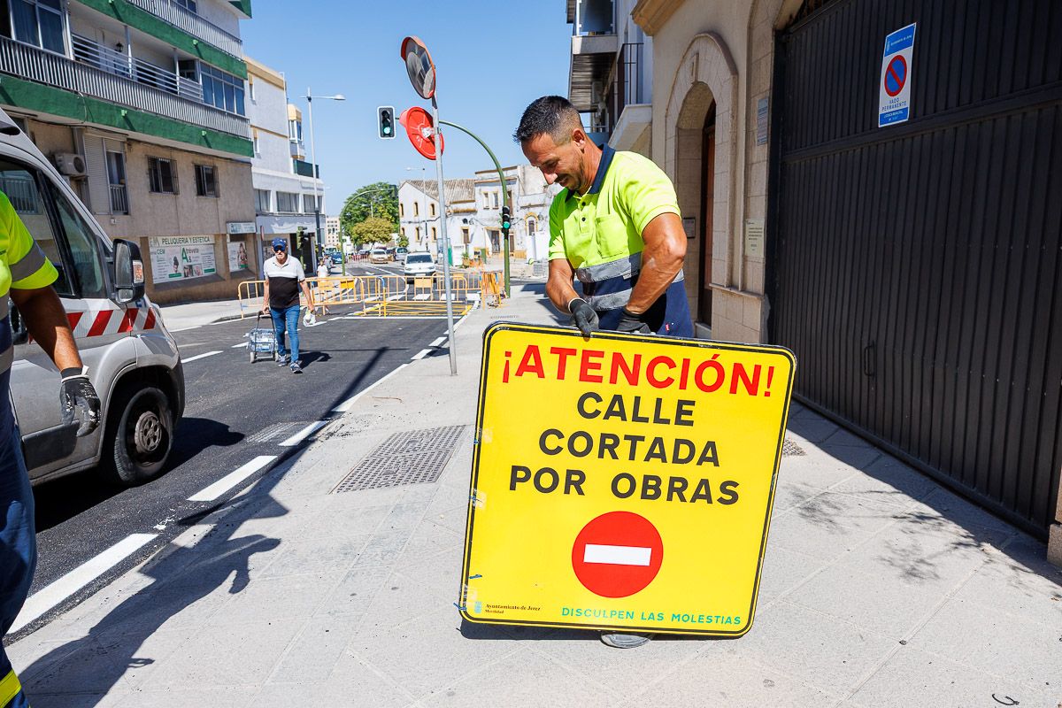 n operario retira el cartel de la calle cortada por obras en Muleros.