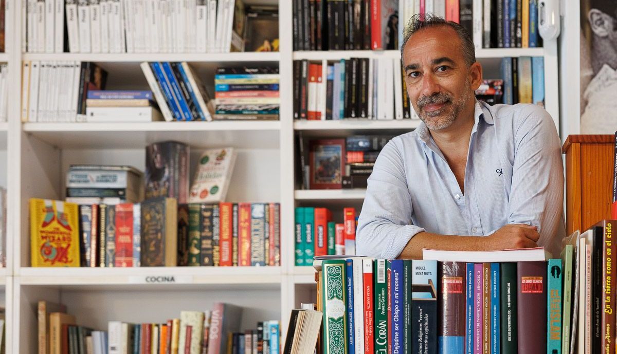 Adrian rodeado de los libros dispuestos en las estanterías. 