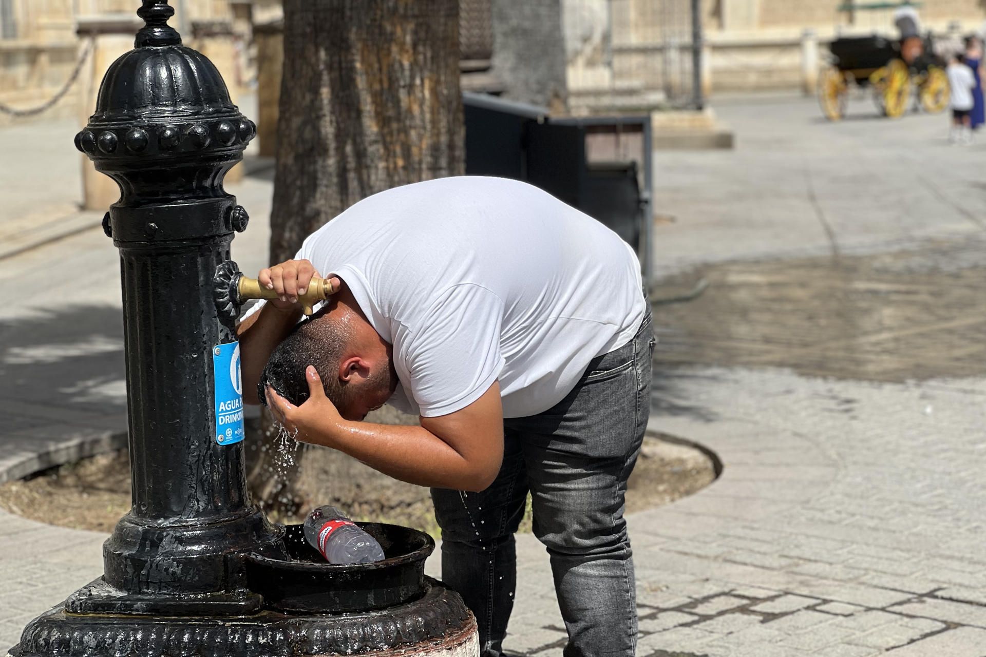 Un hombre aliviándose con agua de una fuente.
