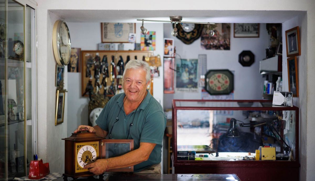 El relojero con uno de pared de los muchos que tiene en su taller. 