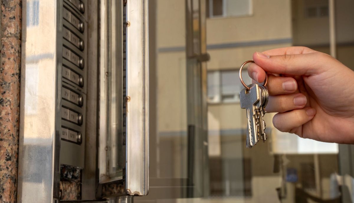 Un joven sostiene las llaves de su nuevo piso de alquiler.