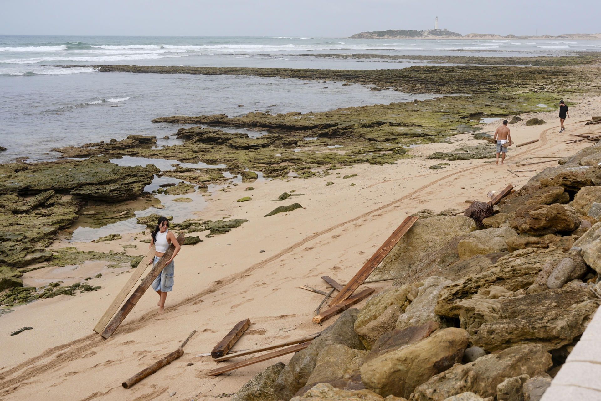Personas en la playa de Los Caños de Meca, con tablas en las manos de los destrozos provocados por el mar de fondo. Personas en la playa de Los Caños de Meca, con tablas en las manos de los destrozos provocados por el mar de fondo.