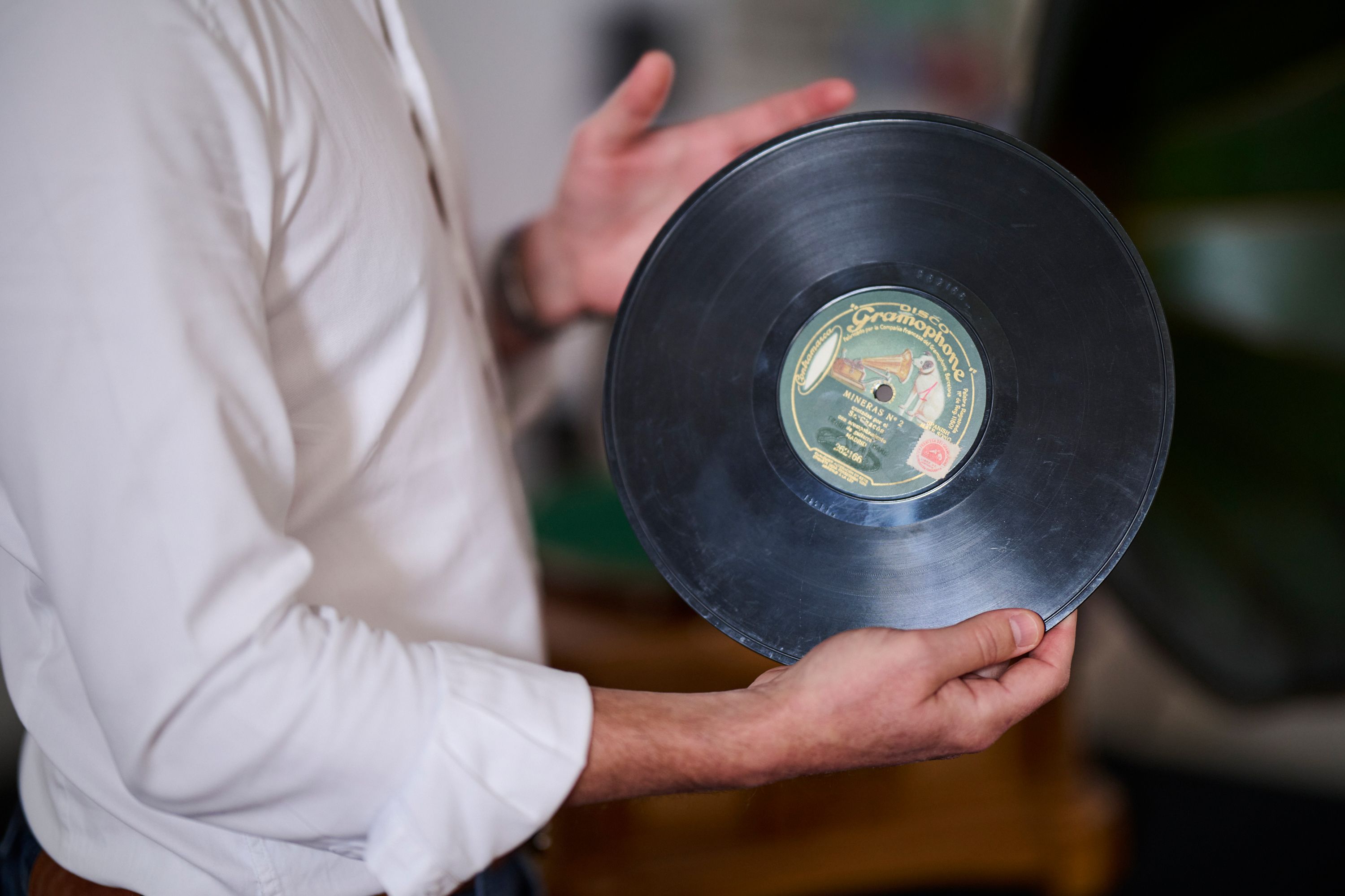 Carlos Martín Ballester mostrando el disco de pizarra que recoger la minera número dos de Antonio Chacón, en la que Ramón Montoya lo acompaña a la guitarra.