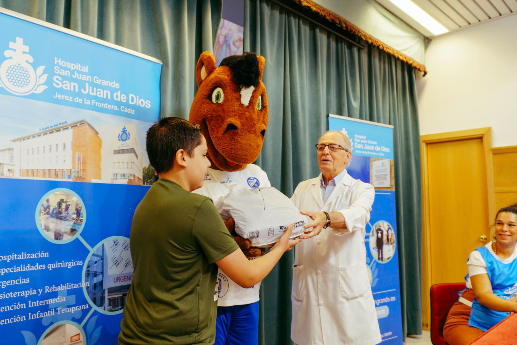 La mascota del Xerez Deportivo entrega materiales a un niño.