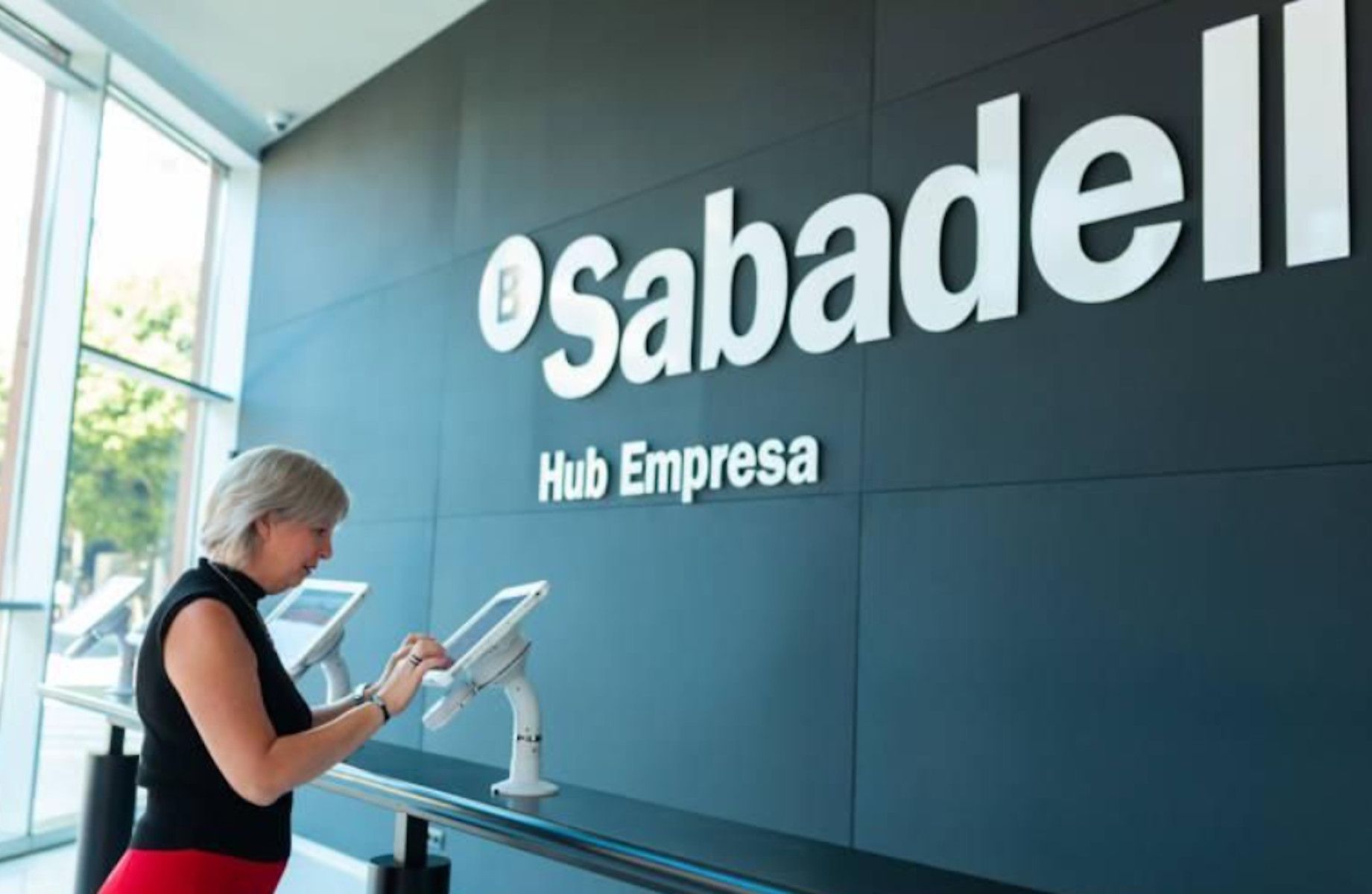 Una mujer, realiza sus operaciones en una sucursal del banco Sabadell.