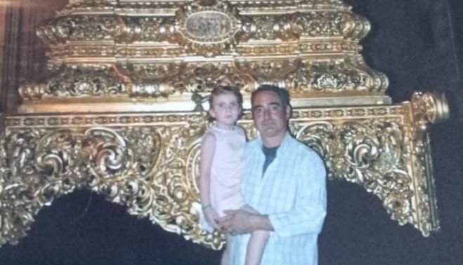 Con su hija en brazos ante el paso del Santo Crucifijo, del que fue costalero.