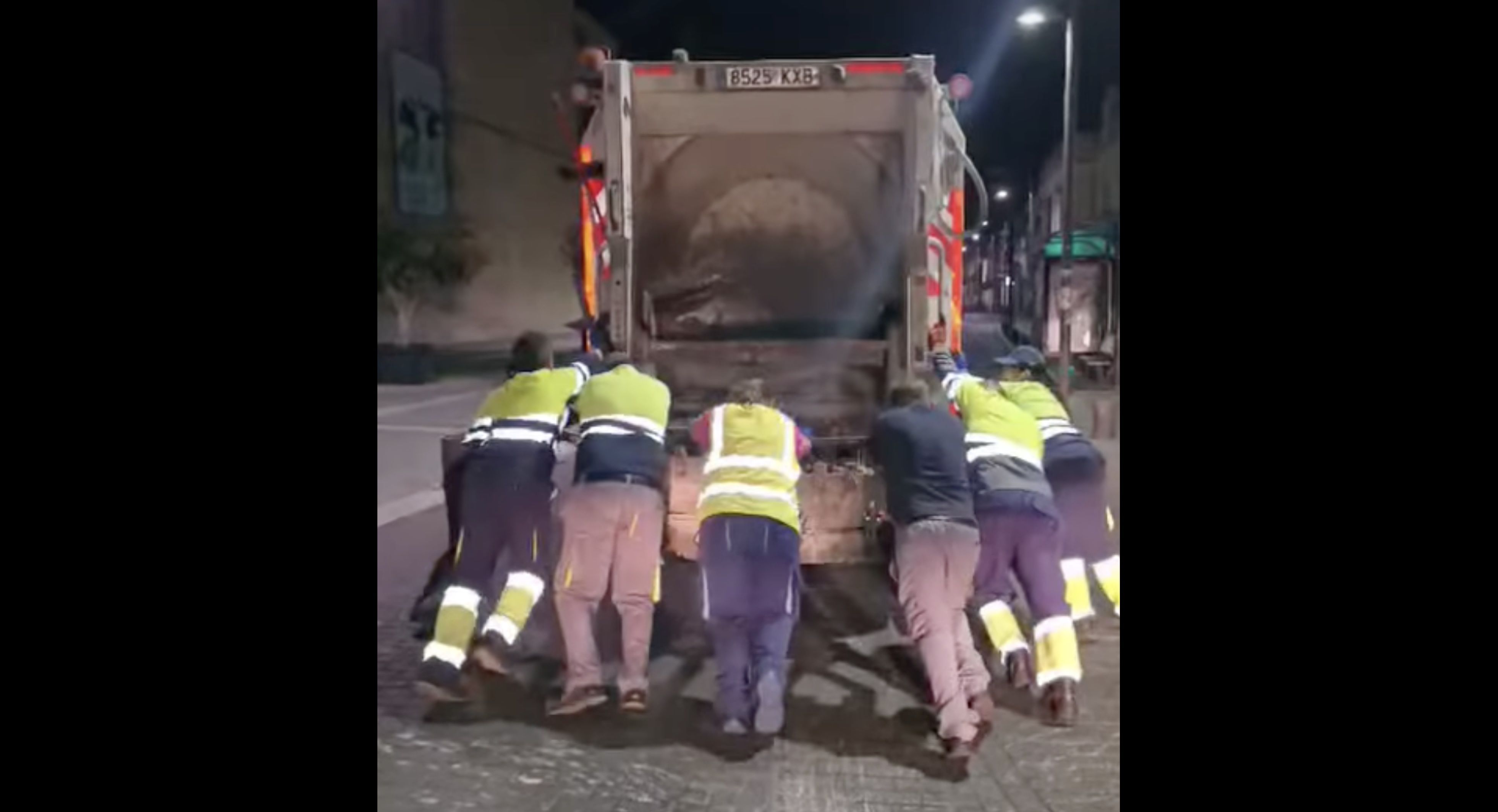Trabajadores empujando el camión de basura en Sanlúcar.